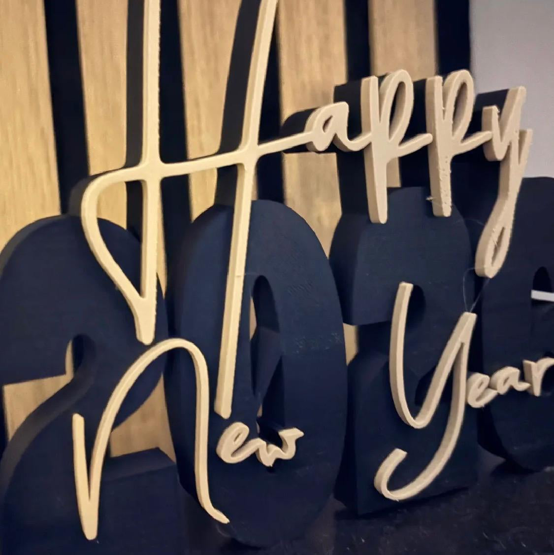 Decorative 'Happy New Year' sign with black and gold letters on a wooden background