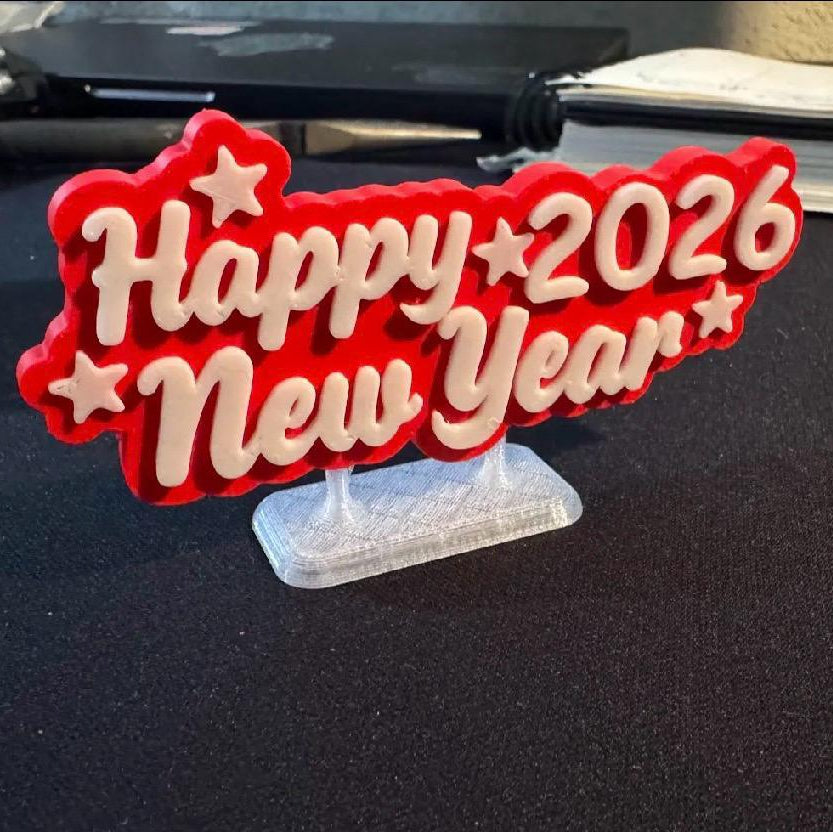 Red and white 'Happy New Year 2026' decoration on a stand with a black background